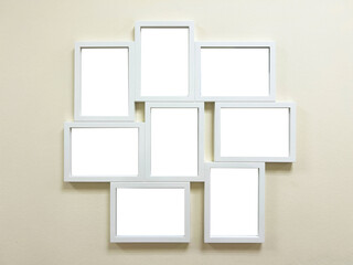 Many blank empty photo frames on light wall background.