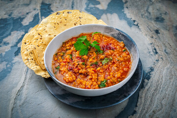 Indian dal fry red lentils with chili papadam servied as close-up in a design bowl