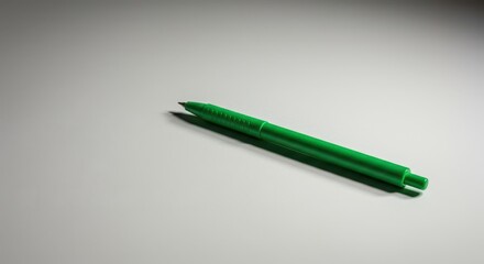 A vibrant green writing pen rests diagonally on a clean, light surface, ready to be used for schoolwork or office tasks, graphic, write, closeup