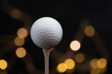 Golf used ball on a tee on a black background close-up