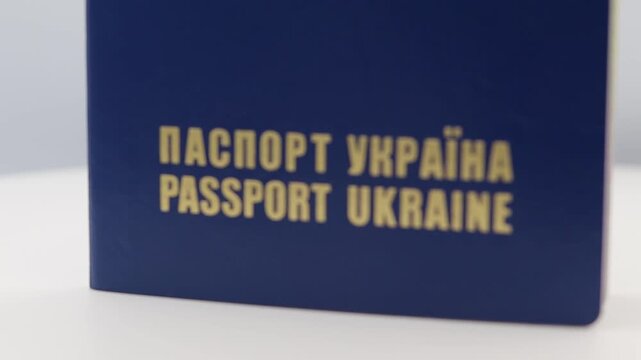 A detailed close-up shot of a blue Ukrainian passport rotating smoothly on a white turntable. 