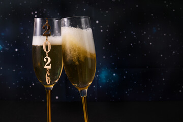 New Year Celebration. Two champagne glasses against a starry backdrop celebrating 2026.