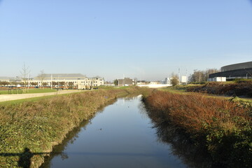 Fototapeta premium La Haine coulant paisiblement sous un ciel bleu d'hiver à Mons (Hainaut)