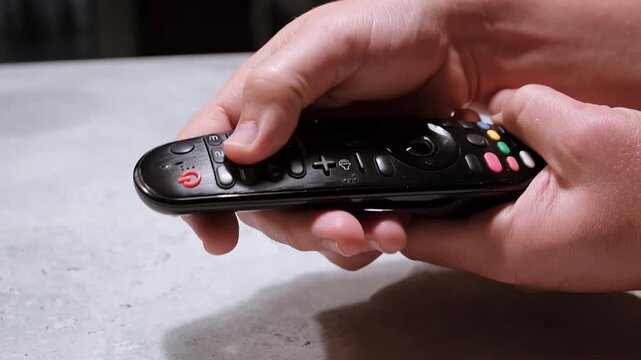 Hand Holding a Remote Control and entering the password. Press the button to reduce the sound. Person browsing various streaming services. Watching TV and selects the channel. High quality 4k footage.