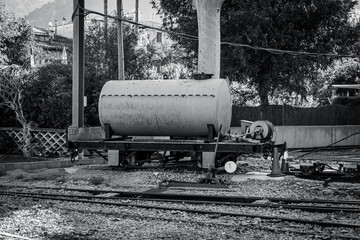 Old railway tanker wagon on narrow gauge tracks in an outdoor industrial setting. Vintage rail transport equipment.