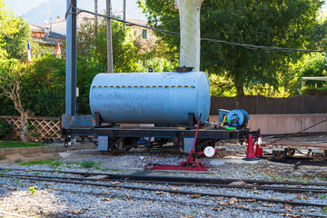 Old railway tanker wagon on narrow gauge tracks in an outdoor industrial setting. Vintage rail transport equipment.