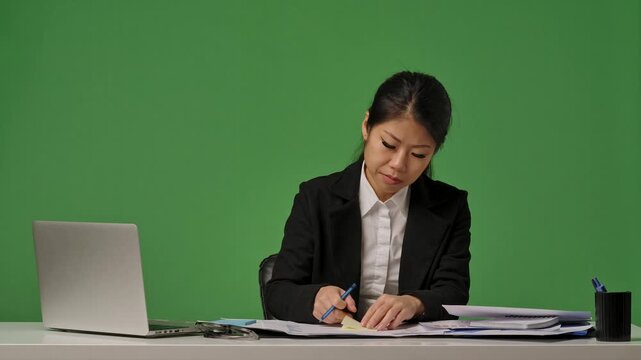 A young Korean businesswoman in a black suit with an SOS sticker on her forehead suffers from fatigue and overwork