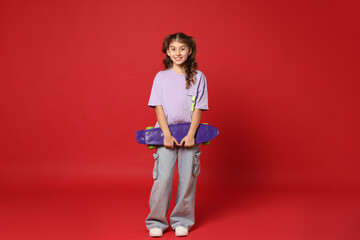 Smiling girl with penny board on red background