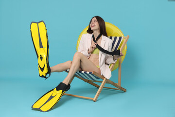 Businesswoman with flippers in deck chair on light blue background © New Africa