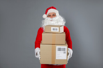 Santa Claus with parcels on grey background