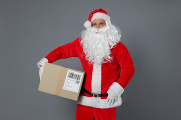 Santa Claus with parcel on grey background