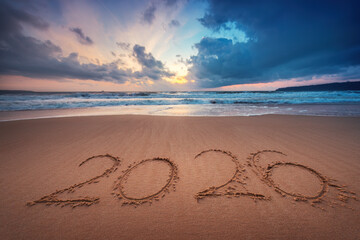 Happy New Year 2026 text on the sea sand and wave on the beach shore