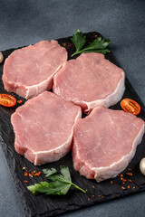 Raw pork loin steak cuts on slate board