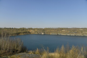 Fototapeta premium Ancienne carrière aux eaux cristallines bleutées sous un ciel clair à Écaussinnes-d'Enghien (Soignies)