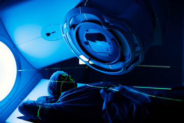 Linear accelerator in oncology treatment room, with patient positioned beneath machine, showcasing...