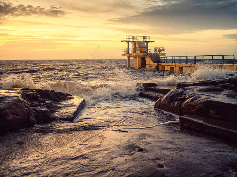 Blackrock diving tower on Salthill promenade in Galway city, Ireland. Popular city landmark. Scenic warm sun rise clouds and wild Atlantic ocean with waves. Travel and tourism.