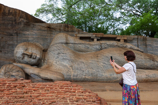 A tourist takes a picture of an ancient reclining Buddha statue at the Gal Vihara temple. Polonnaruwa. Sri Lanka