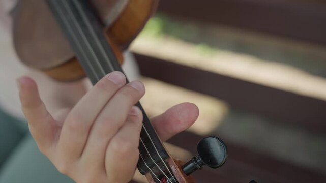Young Girl Positioning Fingers On Violin, Precise Violin Fingering Practiced In Warm Sunlight, Skilled Girl Carefully Practicing Violin Finger Placement During Sunny Daytime Session