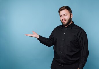 Man shows direction with open hand against a blue background in a simple setting during the day