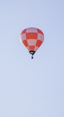Orange and White Checkered Hot Air Balloon Soaring in Clear Blue Sky