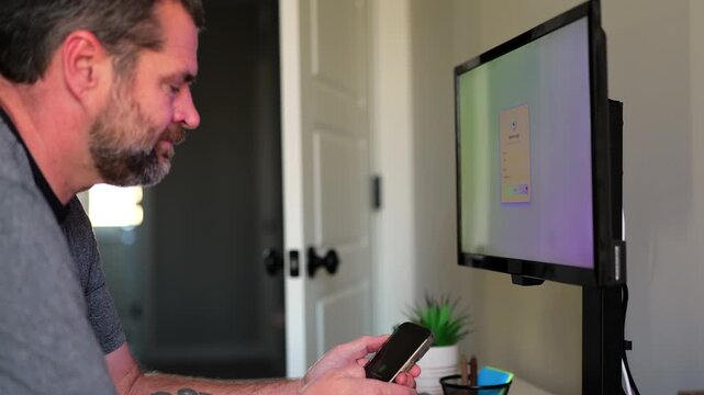 Middle Aged Man Working From Home Remotely is Prompted for Multi Factor Authentication Approval While Signing In Work Computer Cybersecurity Concept