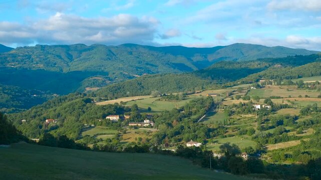 Shadows moving across italian countryside landscape. Sunlight illuminates green hills, fields, and houses in the italian countryside, with shadows gradually lengthening as the sun moves across the sky