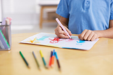 Cute little boy drawing family at wooden table indoors, closeup