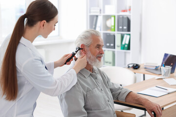 Fototapeta premium Hearing test. Doctor examining patient’s ear with otoscope in clinic