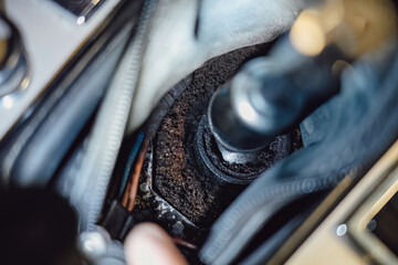 Mechanic's hand installing or repairing the center console trim around the gear shift lever inside a vintage car.