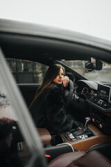 A photograph, a portrait of a beautiful young woman, a female model in a fur coat, in women's lingerie, sitting inside an expensive car.