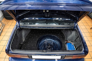 Car audio system installation: amplifier and wiring setup in a clean vehicle trunk. Professional customization and technical maintenance for premium car sound.