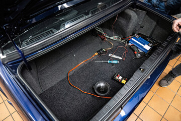 Car audio system installation: amplifier and wiring setup in a clean vehicle trunk. Professional customization and technical maintenance for premium car sound.