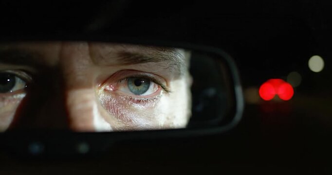 Driver eye reflected in rearview mirror at night. Transportation concept.