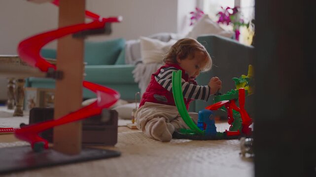 Toddler adjusting toy pieces while seated on floor, careful movements curiosity and persistence revealing early problem solving during independent play at home