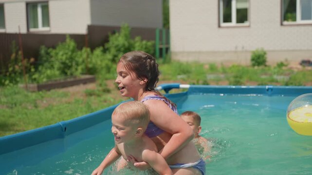 Young Sister Shares Joyful Bath Time, Elder Sister Indulges Little Sibling In Backyard Water Play, Older Sibling Lovingly Carries Young Brother During Lively Pool Splash Session Under Sunny Sky