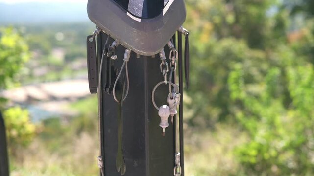 key cluster hanging on pole amid greenery near Johnson City, macro view of metallic keys and rings swaying, textured pole and verdant blurred background, warm summer light, subtle hiking