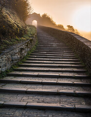 Obraz premium Stone stairway leading uphill to arched entrance on a foggy morning in Yorkshire, England