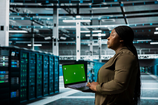 Data center admin using isolated screen laptop to automate anomaly detection. Server farm worker using chroma key notebook, minimizing downtime through predictive maintenance