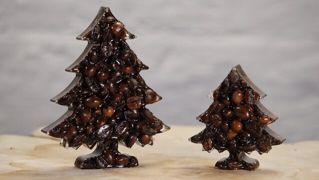 Two Christmas trees of different sizes made from roasted coffee beans on a light background. Creative holiday food concept symbolizing warmth, aroma, and festive caf&eacute; culture, ideal for coffee brandin
