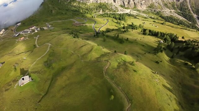 aerial lonely chalet on emerald hillside; travel storyteller frames solitary stone hut amid sweeping green folds and meandering footpaths, peaceful rural mood with distant cliffs and soft