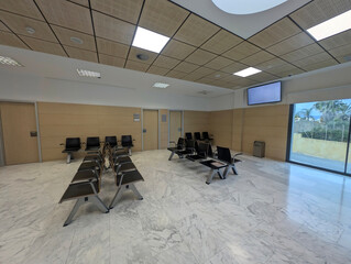 Modern spacious hospital or clinic patients waiting room area with empty chairs. Clean and illuminated medical facility, healthcare, health, contemporary interior architecture, comfort, tranquility.	
