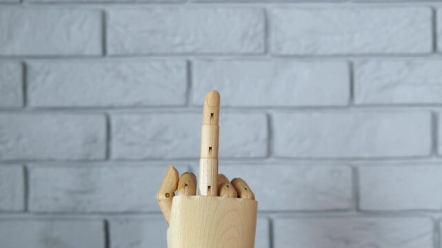 Wooden mannequin hand making obscene middle finger gesture. Articulated wooden artist's mannequin hand slowly rotating while showing an offensive middle finger gesture