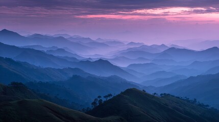 Fototapeta premium A serene mountain range, shrouded in a purple and blue mist, viewed from a high vantage point at sunset. Light softly diffuses