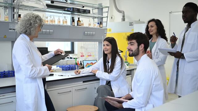 Senior female professor lecturing diverse science students in a university laboratory