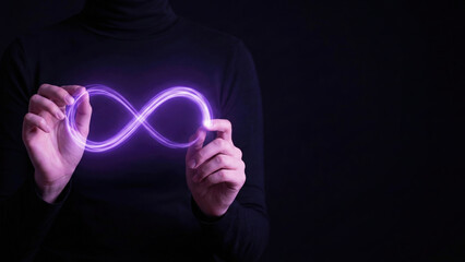 Purple neon infinity symbol held between two hands on dark background expressing endless connection and energy