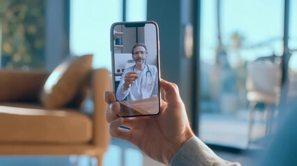 A close up of a hand holding a phone shows a doctor consulting via video chat, highlighting remote medical advice. The scene reflects the rise of digital health and online medical consultations