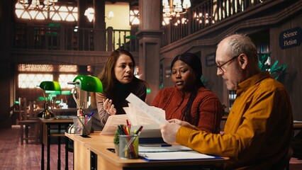 Actors group in library prepare for a dramatic theatre role play, focused on dialogue memorization and script study. People working on delivering the best classic drama performance.