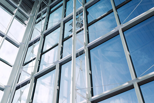 Modern glass facade of office building. Steel structure and large windows against blue sky. Contemporary architecture detail from below. Corporate business building exterior. Urban design concept - Powered by Adobe