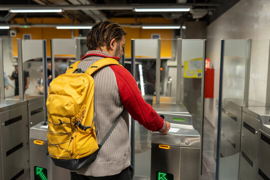 Adult man tapping ticket on turnstile entering subway station, public transport travel