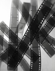 Fototapeta premium Abstract collage of old celluloid film strips tangled together. These retro cinema reels show perforations and wear marks suggesting a vintage or damaged aesthetic.